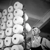 En man inspekterar trådrullar på spinneriet, Nääs.