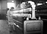 En kvinna arbetar vid spinningmaskinen på Nääs Fabrik.
