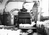 En man arbetar med att bryta balar med bomull. Nääs fabrik i Tollered. 
