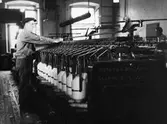 En man  står vid ringspinningsmaskinen. Nääs fabrik i Tollered.