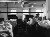 En matar in bomull i rensmaskinen. Nääs fabrik i Tollered.