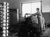 En kvinna spinner trådar. Nääs fabrik i Tollered.