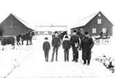 Gården Berg i Ugglarp år 1886. Anders, Gustav, Karl, Birger och lille Johan med mors porträtt på rocken, samt Patron på Berg, alla med efternamnet Gustavsson. I en hästdragen vagn sitter tjänstefolket Karolina och Sven-August. På sidan om vägen står  en ko och en vagn med ett par hästar. En man sitter på kuskbocken. Det är vinter och lite snö på marken.