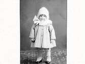 En liten flicka klädd i vinterkläder. Reinhold Bengtsson, Varberg beställde bilden och är troligen barnets far. Barnporträtt.