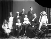 Familjebild i ateljé med ett föräldrapar och deras åtta barn. Fyra pojkar, tre flickor och ett spädbarn.