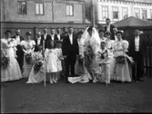 Gruppbild av brudpar med bröllopsgäster, tagen i fotografens trädgård. Varberg, kv Bagaren, Prästgatan