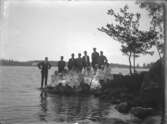 En grupp människor på klipphäll vid sjöstrand, Ryd, Småland.