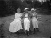 Tre kvinnor sittande på en parkbänk. Ryd, Småland.