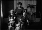 Kvinna, sittande med två flickor med deras dockor och nallar.
Västerås.