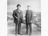 Ateljéfoto av en äldre och en yngre man. Fonden ska ge illusionen av att de är på promenad längs havet med Varbergs fästning i bakgrunden. Den äldre mannen har kubb och käpp; den yngre en skärmmössa.