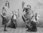 Fyra folkloreklädda flickor i dansposer med bandförsedda tamburiner. (Se även bild MR2_1043 och MR2_1046)