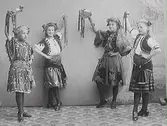 Fyra folkloreklädda flickor i dansposer med bandförsedda tamburiner. (Se även bild MR2_1042 och MR2_1046)