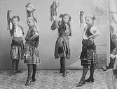 Fyra folkloreklädda flickor i dansposer med bandförsedda tamburiner. (Se även bild MR2_1042 och MR2_1043)