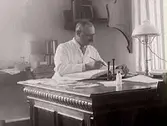 Överläkare Constantin Pettersson vid sitt skrivbord med en elektrisk lampa på.