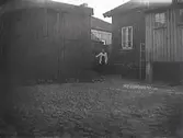 En kvinna mellan husen på en bakgård, troligen i Varberg. Gården är belagd med kullersten. (Se även bild MR3_1715)