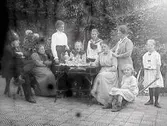 Kaffe i Mathilda Ranchs trädgård med vänner, systrar och syskonbarn. Från vänster: Elof Ernwald med en tehuva på huvudet, okänd, Hulda Lindh, Anna-Greta Alling?, Ingrid Alling, Nathalia Alling?, Mathilda Ranch, Anna-Stina Alling och en okänd flicka. (Något skadad bild)