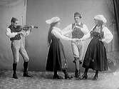 Folkdans. En fiolspelare och en man inbegripen i dans med två kvinnor. (Se även bilderna MR2_1690, 1699, 1735)