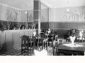 Interiör från restaurangen på Grand Hotel i Falkenberg. Väggmålningar av Arvid Carlsson, vilka ser ut att föreställa olika yrken. Golvet är rutigt och inredningen tidsenlig - kanske har lokalen nyligen renoverats?