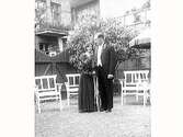 Brudpar. Bröllopsbild. Mejerist Eriksson med fru fotograferade bland stolar på en innergård.