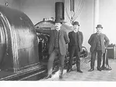 Interiör från Varbergs Ångkraftverk, uppfört 1908 i Varbergs hamn som reservkraftverk till Yngeredsfors kraftstation i Ätran, uppfört 1907. Männen i kubbar bredvid ångturbinen är fr v: herr Östlund från ASEA, herr Lundberg från Yngeredsfors Kraftverk AB och herr Lundgren från de Laval. (Se även bildnr MR2_921)