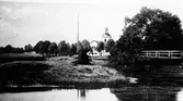 Landskyrkan med Säveån framför och gångbron till höger. Gångbron över Säveån vid Nolby 