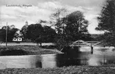Landskyrkan med Säveån framför och till höger gångbron. Träbron över Säveån vid Nolby, 