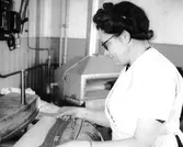 En kvinna arbetar med en maskin som skär tyger på Gustafson & Werner i kvarteret Gustaf 2.