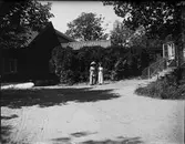 Två kvinnor på grusgången vid byggnader, Sätra brunn, Sala