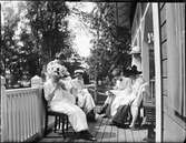Kvinnor sitter på verandan och handarbetar, Sätra brunn, Sala