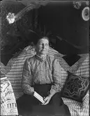 Kvinna sitter i soffa med en bok i handen, Uppland