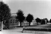 En liten flicka sitter på en låg mur vid fabriksområdet till Alingsås Bomullsväveri.
Nya fabriken i kvarteret Vimpeln. Fabriksområdets västra del. Foto mot söder.