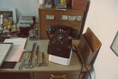 Diverse skrivbordsattrialjer och gammal telefon.