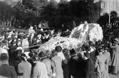 Barnens dag 1938. Blomsterflicka åker på en blombeklädd vagn i paraden förbi folksamlingen.