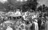 Barnens dag 1938. Pojkar i hattar och mössor med insamlingsbössor åker på ett flak åker förbi folksamlingen under paraden.