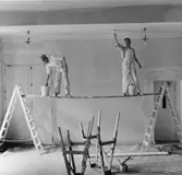 Trapphallen på 1 tr. Till höger hiss och till vänster dörren till
receptionsrummet. Målarna Dan Velander och Kalle Malm.