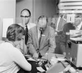 De utländska besökarna köper frimärken av fröken Berit Nyholm, i
moderna postkontoret på 2 trappor.