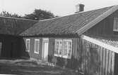 Lantgård, Knastås i Onsala. Dörren har ett smalt överljus och de bortre fönstren är försedda med fönsterluckor som är stängda.