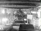 Interiörbild av Onsala kyrka tagen från orgelläktaren. Altarring och altaruppsats omgiven av kaptensläktarna där de hemkomna sjökaptenerna satt efter sina seglatser. I förgrunden till höger predikstolen. Över mittgången hänger votivskepp. Taket är rikt bemålat.