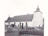 Kyrkan i Onsala sedd från nordväst. Trätornet är från 1700-talets mitt. I förgrunden en grav med smidesstaket.
