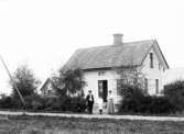 Familj framför hus i Fjugesta, 1909