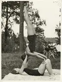 Två gymnastikflickor övar akrobatik på en gräsmatta. 1930-tal.