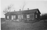 Bostadshus nära Råö i Onsala. Huset har två ingångar till var sin bostad med trappor; den vänstra av sten, den högra med plansteg av trä. Vid var trappa står ett träd. Fasaden på vänstra och mindre delen av huset ser ut att vara rödmålad, medan fasaden på den högra antingen är omålad eller har nött färgning.
(Se även bild G8883)
