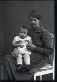 Ateljéfoto med en ung kvinna som har ett litet barn i knät. Beställare: Manda Johansson.