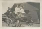 En kusk, två kvinnor och en flicka sitter i en droska utanför ladan vid Stretereds skolhem cirka 1920. Bildtext från album: 