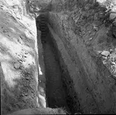 Utgrävningen av schakt C genom södra delen av borgkullen vid Rumlaborg i Huskvarna är helt avslutad. Fotot är taget i samband med arkeologiska undersökningar vid borgen sommaren 1937. För att förhindra ras grävdes schaktet i tre terasseringar som vardera var upp till 1,5 meter djupa. Som bredast på toppen var schaktet tre meter brett.