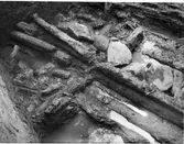 Närbild på timmer och stenar vid Rumlaborg i Huskvarna. Lämningarna påträffades i norra delen av schakt G på sydvästra sidan av borgkullen i samband med en arkeologisk undersökning sommaren 1942.