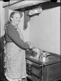 Kvinna lagar mat på vedspis, Uppland 1948