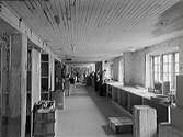 Monarks centrallager i Rommelska fastighetens gårdshus, med långbänk utmed fönster, trälårar, hyllor och personal längst bort i bild. (Se även bild nr GB1_1001)