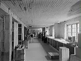 Monarks centrallager i Rommelska fastighetens gårdshus, med långbänk utmed fönster, trälårar, hyllor och personal längst bort i bild. (Se även bild nr GB1_1001)