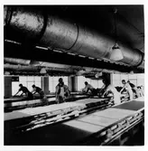 Interiörbild från SILFAs tryckeri. Vid de långa tryckborden arbetar 9 män.